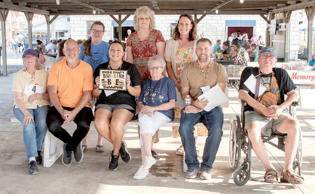 PARTICIPATING in the first Community Spelling Bee at the Rooks County Free Fair were spellers (front row, from left): Leslie Fogle, Kevin Kallenberg, spelling champion Julie Glendening, Hazel Laporte, Jeff Riener, and Frank Austin. Helping with the contest in the back row were Sierra Reed (Stockton Public Library), announcer Heather Stamper Voss, and Jami Dewey (Plainville Public Library).