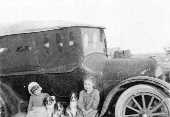 THE YEAR OF THIS PHOTO IS UNKNOWN, but the two little girls pictured with their puppies are Rosalie Smee Stithem and Mary Pearl Smee. This was their father's first car, which featured side curtains.