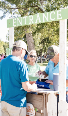 DENNIS BEDORE handles the cash rush at the Pumpkin Patch Festival entrance, as Kelly and Vickie Desmarteau of Stockton pay their way into the fun!