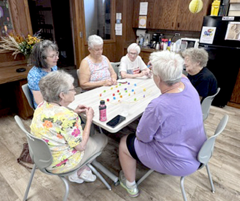 A TABLE OF WOMEN having a ball playing the magnet game and visiting all morning Tuesday at the adult social/coffee hour.