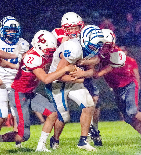 RYLAN BASART protects the ball as he drags his Logan/Palco defenders to pick up yardage during the game at Logan.