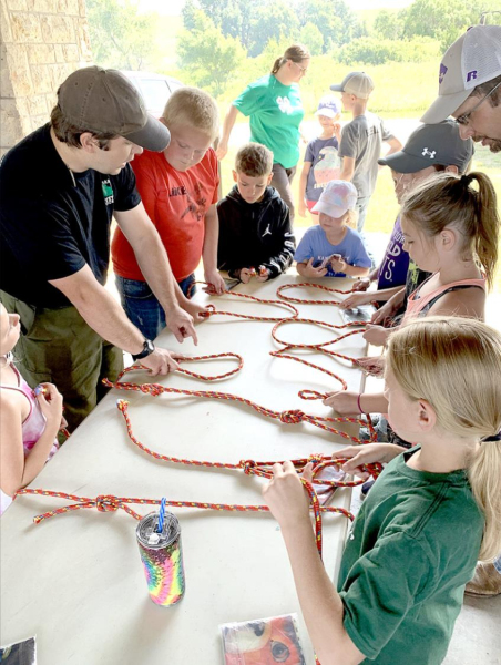 TYING ROPES with Chris Hanson, pictured left in dark shirt, was one of the many tasks the kids enjoyed at the Outdoor Adventure Day Camp held at Rooks State Fishing Lake.