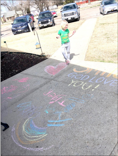 MALEA JONES is standing by the sidewalk chalk masterpiece she and her big sister Shoni created for the residents at the Solomon Valley Manor.