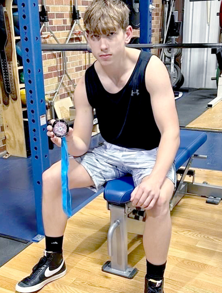 CASON IWANSKI WAS PRESENTED A MEDAL on Friday, January 20, from the Blue Ace Power Invitational for placing second overall in his weight class of 29 competitors. Iwanski lifted a total of 825 pounds at the virtual event. He was a fourthplace finisher at State last season. (Courtesy Photo)