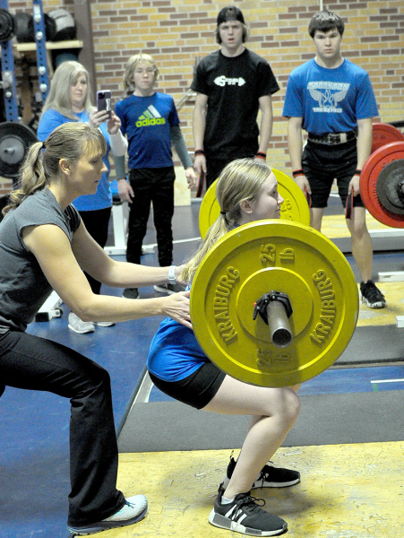 KATY POST, spotted by Coach Janet Kuhlmann, looks to succeed with this squat lift during the virtual powerlifting meet held recently.