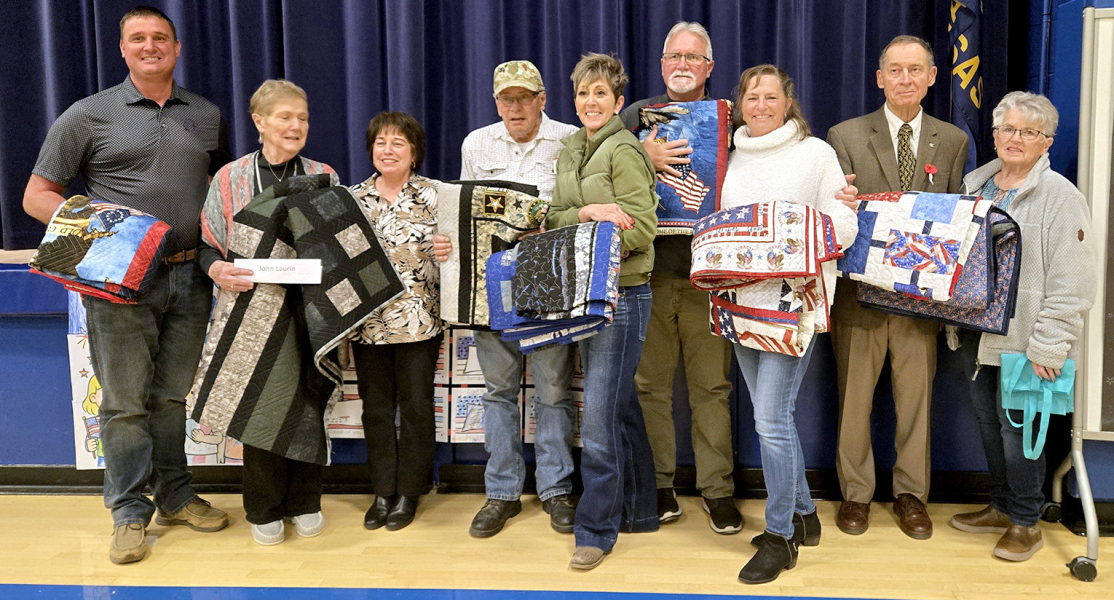 HOLDING THEIR QUILTS OF VALOR presented to the veterans at the Veterans Day program on Tuesday, November 11th at Stockton High School are (from left) Joel Laurin, Irma Newell (representing John Laurin), Cindy Newell (who made six of the seven quilts), Ken Dreiling, Jill Jantz, Jack Laurin, Mary Jo Laurin, Thomas Riffe, and Diane Maddy (who made Riffe's quilt).