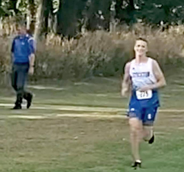 LOOKING RATHER RELAXED, Johnny Hamel, with Coach Chris Graham in the background, traverses the cross country course in Norton. Hamel won the race by 13 seconds. (Courtesy Photo)