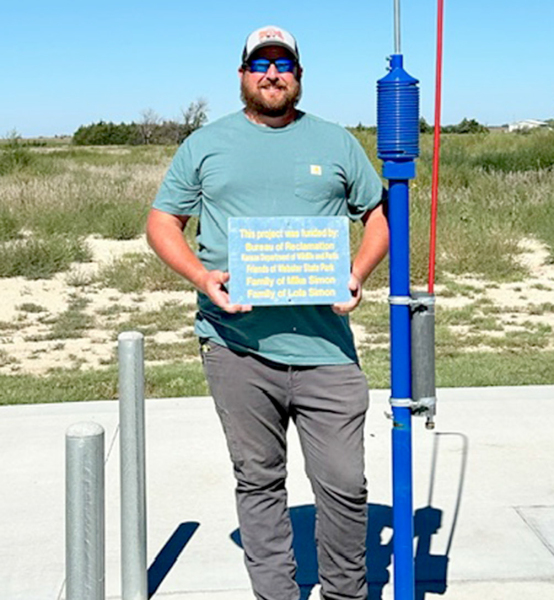 CHAD SIMON, representing his late father, Mike, and grandmother, Lola, holds the plaque for the new dump station at Webster State Park. (Picture courtesy of Chris Palmer.)