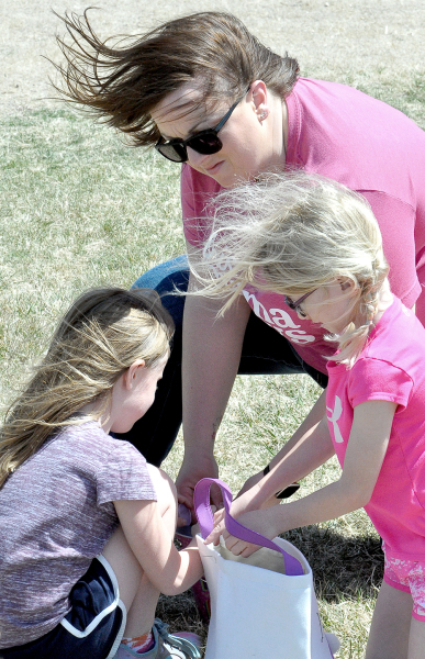 FINLEY PETERSON, CHELSEY PETERSON and Hadlyn Becker look for treasures in their baskets following the Sigma Phi ESA Easter Egg Hunt held on April 15 at the Lower City Park.