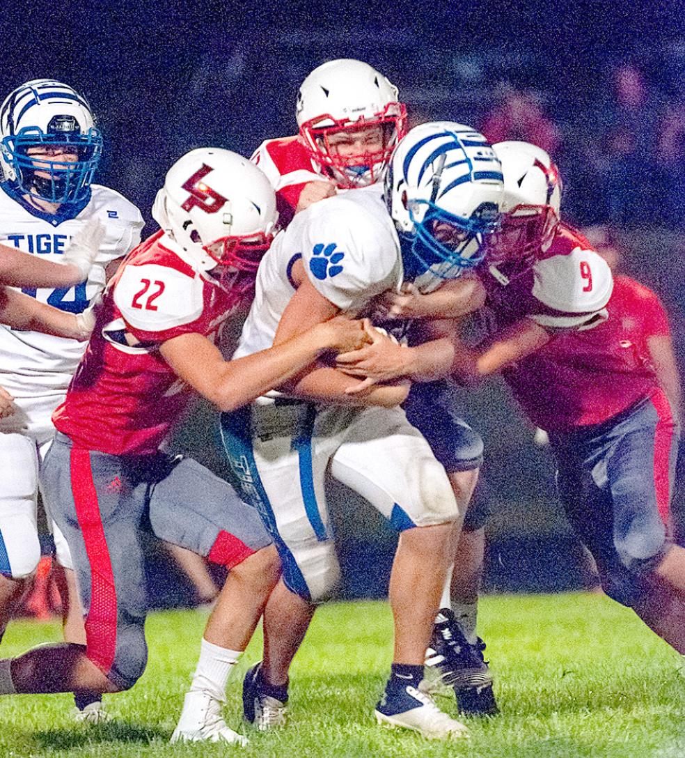 RYLAN BASART protects the ball as he drags his Logan/Palco defenders to pick up yardage during the game at Logan.