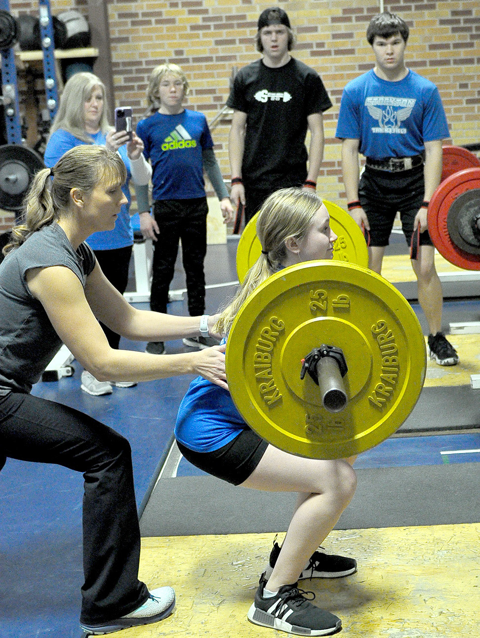 KATY POST, spotted by Coach Janet Kuhlmann, looks to succeed with this squat lift during the virtual powerlifting meet held recently.