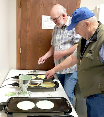 FLIPPIN’ GREEN FLAPJACKS for the Lions Club on Sunday, March 13, were two “veteran flippers,” Henry Sander (in the back) and Dennis Bedore.