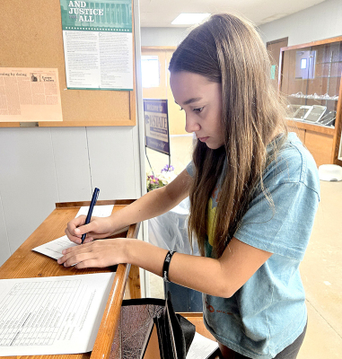 KAYLYN BECKER with Eager Beaver 4-H writes her information on the entry cards for her arts and crafts items at the Rooks County Free Fair.