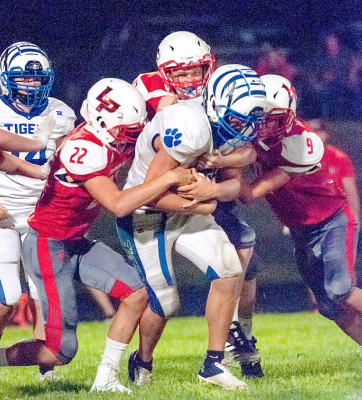 RYLAN BASART protects the ball as he drags his Logan/Palco defenders to pick up yardage during the game at Logan.