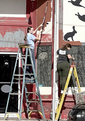 STOCKTON HIGH SCHOOL seniors Cappi Hoeting and Addie Struckhoff roll a coat of paint onto Baxter’s building during Stockton’s PRIDE Day.