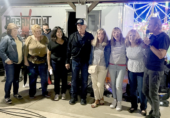 THE STOCKTON HIGH SCHOOL CLASS OF 1974 held a reunion the weekend of the Rooks County Free Fair. On Friday evening, a group of them hit the Solutions North Bank Pavilion to listen to the ‘80s Rock Tribute band, PARAMOUNT. The band’s lead singer, Eddie Light, invited them onstage for some lighthearted fun. From left are: Kris (Clark) Kuck, Deb (Miller) Roy, Cheryl (Turnbull) Dunning, Doug Stewart, Jolene (Desbien) Hamel, Jeanie (Stewart) Brown, Candace (Spencer) Orona, and Light.