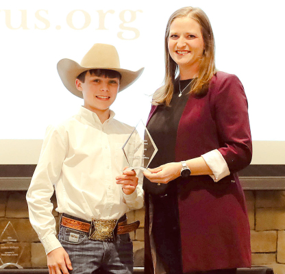 ELI ATKISSON, STOCKTON, left, was awarded the Kansas Angus Auxiliary Premier Exhibitor award at the 2026 Kansas Angus Association Annual Meeting and Banquet, Feb. 28 in Hutchinson, Kan. Pictured presenting the award is Esther Tarpoff, Kansas Angus Auxiliary president, right. Photo by Anne Lampe, Kansas Angus Association