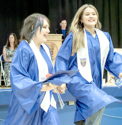 WITH DIPLOMAS IN HAND AND SMILES ON THEIR FACES, Stockton High School graduates Piper Creighton, left, and Alex Brandon skip their way out of Tiger Gymnasium following Commencement exercises Saturday morning. Stockton High School celebrated 15 graduates in the Class of 2026.
