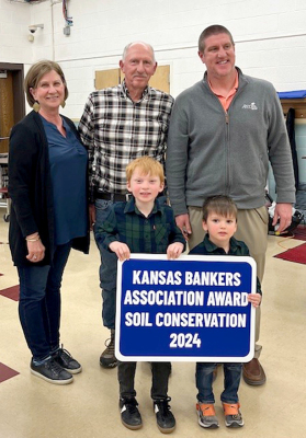 THE 2024 BANKERS SOIL CONSERVATION AWARD was awarded to Dan and Lois Gasper of Stockton. Receiving their award at the Annual Meeting on Monday, January 27th, in Plainville, are back row, from left: Lois Gasper, Dan Gasper, and Scott Schulz with the Astra Bank in Plainville, along with two of the Gaspers’ grandchildren, Finnegan Larson and Sullivan Larson.