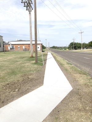 ONE OF THE CITY PROJECTS completed this summer was pouring a sidewalk from the McNulty Log Cabin to Stockton’s Lower City Park entrance for better public access. The sidewalk is on the north side of the cabin and city power plant and makes a safe path for everyone walking to the park to enjoy all the summer sports activities and playground equipment.