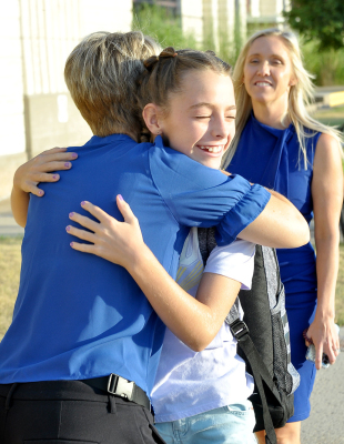 ADDIE DIX gives Stockton Grade School Principal Stacey Green a hug as she walks into school last Friday. Superintendent Sarah Armstrong (right) was also on hand to greet the students on their first day of the 2022-23 school year.