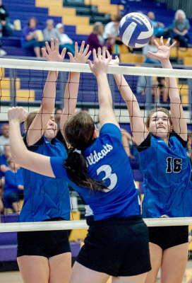 JANAE KELLER AND AUBREY KESLER go up up a double block against a Wallace County opponent at the Trego Invitational tournament.