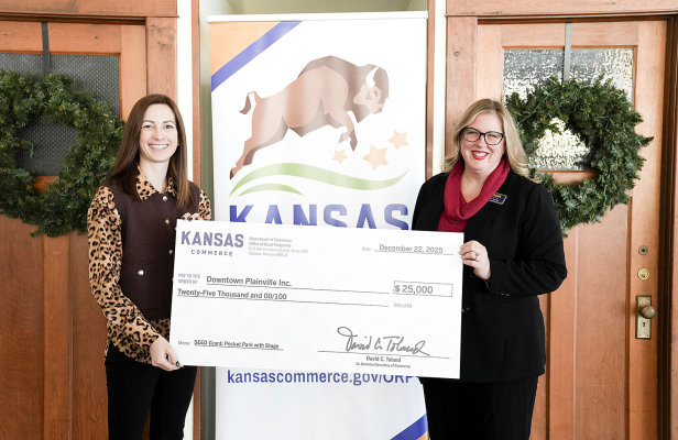 ASHLEY COMEAU, left, representing Downtown Plainville, Inc., accepts a $25,000 SEED grant check from Trisha Purdon, Director of the Office of Rural Prosperity at the Kansas Department of Commerce, to support the transformation of former lumber yard lots in Plainville into a vibrant community space known as 'The Yard.' The presentation took place Monday, Dec. 22, in Yates Center.