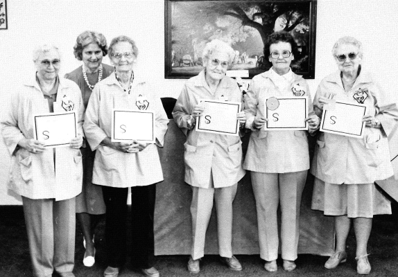 THE ROOKS COUNTY SENIOR COMPANIONS attended the In-Service Training and Recognition on April 6th, 1989, in the Community Room of the Valley View Apartments in Stockton. The ladies who were recognized for their years of service were (from left to right) Doris Eller, Mildred Fischer, Jennie Aust, Opal Wilkerson, Vera Gouldman, and Mary Smee, with featured speaker and presenter Sue George, Director of Health Promotion at Hadley Regional Medical Center, pictured in the background.