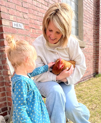 Karen Bouchey and her friendly hen and a young patron at Farm Day Story Time.