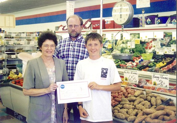 JASON LINDSEY was shown with the $1,000.00 check he had received in a 1997 Pillsbury Scholarship drawing at Webster’s Food Pride. Jason’s grandmother, Jean Lindsey, had registered him in the drawing. They are pictured with Webster’s co-owner at the time, Nick Lowe.