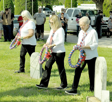 AUXILIARY TO VFW #8873 members, from left, Kathy Creighton, Lisa Gilmore, and Barbara Record, lay the wreaths at the Veterans’ Memorial in the Stockton City Cemetery.