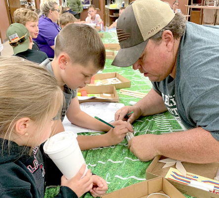 Jamie Keller (far right photo) instructs a youth on how to measure fin placement.
