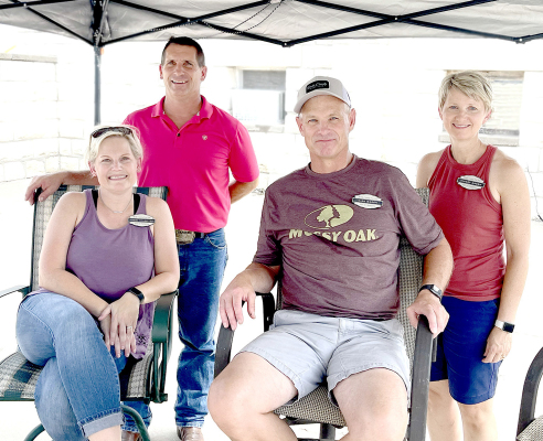 AFTER SPENDING MUCH OF THE YEAR PLANNING,Rooks County Free Fair Board Members Jessica Iwanski and Kirk Green (sitting), along with their spouses, Craig Iwanski and Stacey Green, are ready for an exciting week of Fair activities. The couples were manning the entrance to the Demolition Derby on Sunday. Kirk, along with Rod Becker of Plainville, is a new member on the Board this year.