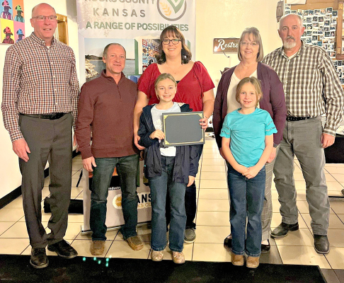 ROOKS COUNTY ECONOMIC DEVELOPMENT DIRECTOR ROGER HRABE, left, with The Daily Grind owners Andy and Chelsey Peterson and their two daughters, Emery and Finley, and Julie and Chris Kriley.