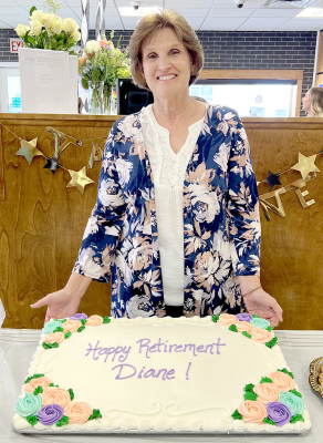 DIANE CREEVAN VOSS stands with her retirement cake during a come-and-go reception held in her honor last Friday at Solutions North Bank. A large group of friends, family, and community members gathered to celebrate and wish her well in retirement. She has been a mainstay of the bank since August of 1980.