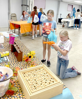 STOCKTON 5TH GRADER EMERY PETERSON tests her shooting skills at the Rooks County Historical Museum’s laser shooting gallery during Give Fest: 2025, while Norah Muir looks on.